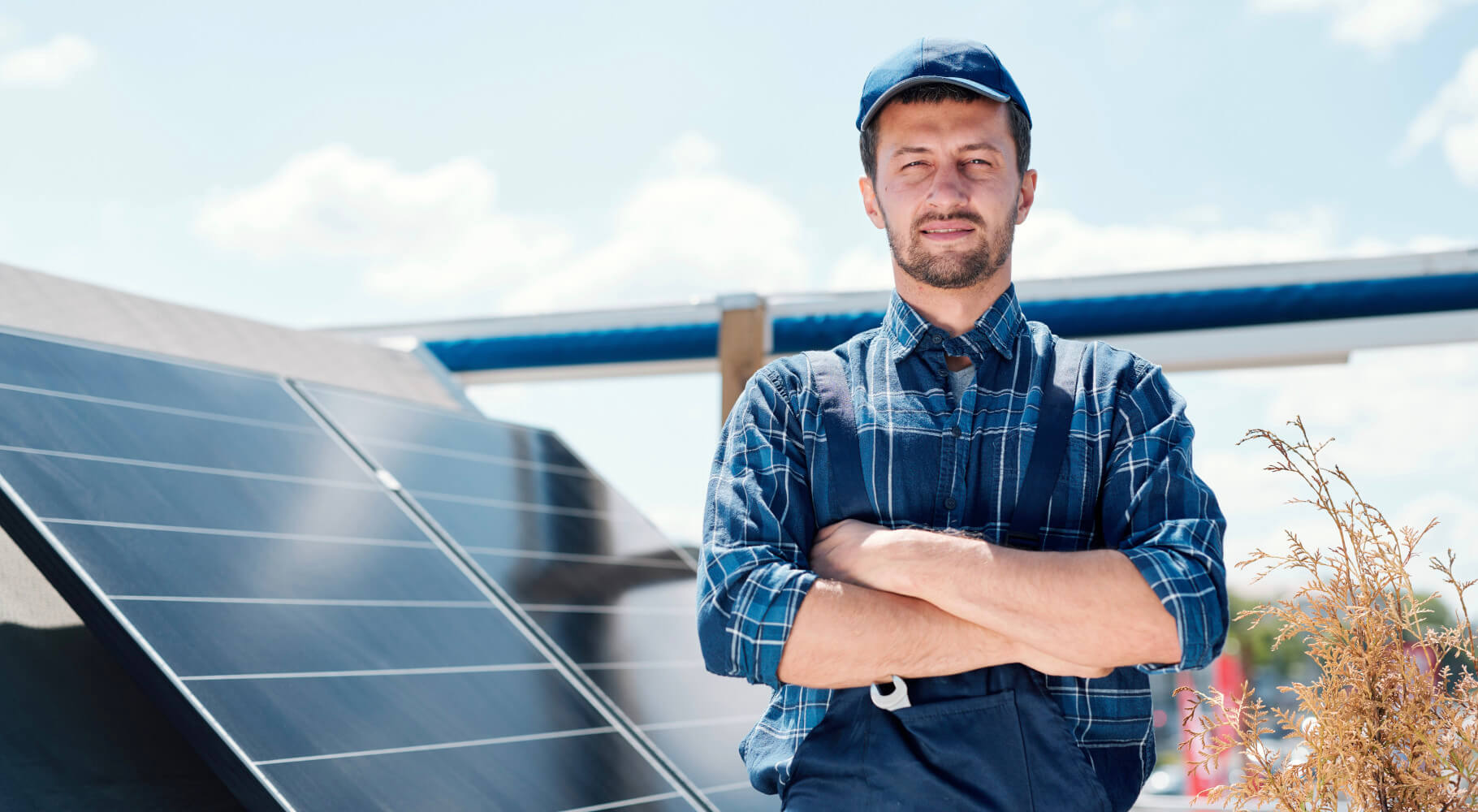 Servicemitarbeiter Solarperfect mit Solarstromanlage Mann mit verschränkten Armen, er steht neben einer Solarstromanlage